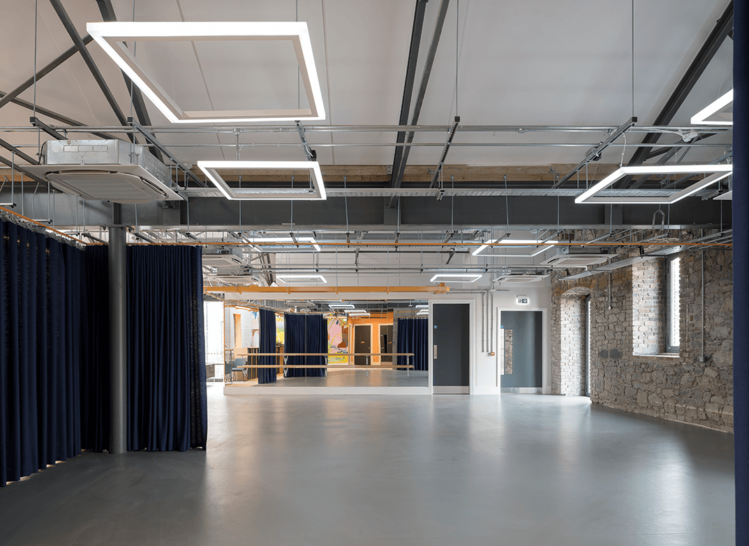 Large open event space featuring a mirrored wall with a ballet barre attached, and curtains for sectioning the space.