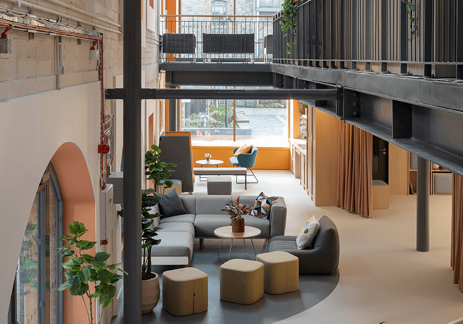 Bright, open lounge area next to the Encore event space with a large sofa, chairs and stools.